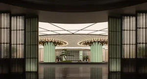 A large building with a green roof and central atrium, surrounded by columns and potted plants, with natural light illuminating the area