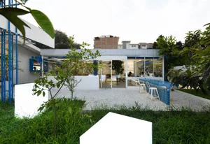 An open modern living area with a large pool, white building, and multiple seating and dining areas