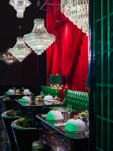 Dining area with tables, chairs, and red curtains, adorned with green and gold decorations, with wine glasses on the tables