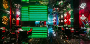 A restaurant interior with green walls and floors, featuring multiple chairs and dining tables in a modern setting