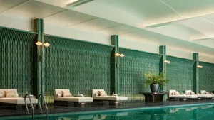 A relaxing poolside area with lounge chairs, couches, and a potted plant, perfect for leisure time
