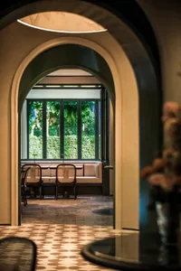 Dining area with a large archway, two chairs, and a dining table surrounded by chairs, giving off a sophisticated atmosphere