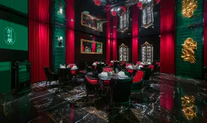Ornate dining area with a large table, black leather chairs, and wine glasses, set in an elegant and sophisticated atmosphere