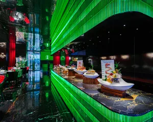 A modern restaurant dining area with multiple tables, green accents, potted plants, and bowls of food on the tables