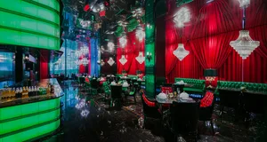 Ornate restaurant interior with red velvet walls, green accents, and cozy dining area with tables and chairs