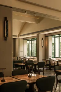 A modern restaurant interior with green walls, wooden and tile flooring, and numerous dining tables and chairs