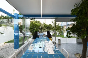 A modern dining area with a glass table, white chairs, and natural light from a window