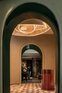 Dining area with a table and chairs surrounded by potted plants, a vase, and a doorway to other rooms, exuding luxury and refinement