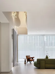 Open modern living area with two couches, a chair, and a large window allowing natural light to fill the space