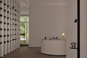 Empty room with white walls and floors, featuring small tables and lamps in a minimalist and clean atmosphere