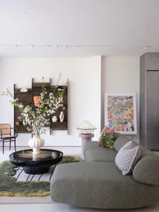 Cozy open living area with a couch, chair, dining table, potted plants, and decorative vases