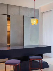 Sleek modern kitchen with grey walls and cabinets, a dining table, and two chairs, surrounded by contemporary design elements