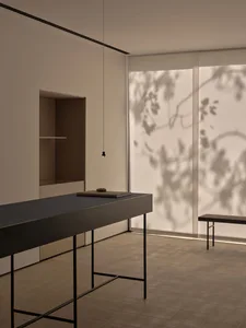 A modern dining space with a wooden table surrounded by metal chairs in a minimalist setting