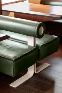 A modern room with a green leather chair on a hardwood floor, surrounded by minimal decor