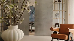 A well-lit living area with a large orange chair, vases, and a potted plant, creating a comfortable atmosphere