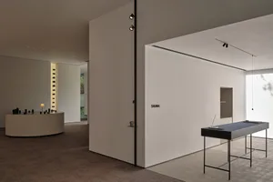 Empty office space with white walls, a black table, and a laptop, creating a calm and organized atmosphere