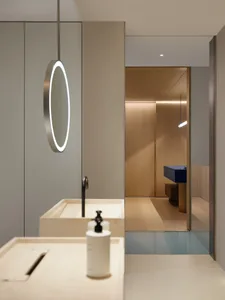 Bathroom with two sinks, a wooden floor, and a circular-framed mirror in a well-lit space