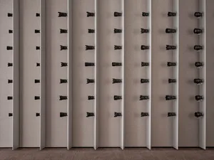 A row of black objects mounted on a wall in a neat and organized manner, possibly in an art gallery or museum setting