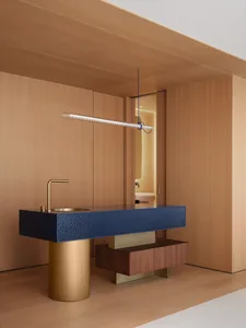 Modern bathroom with a marble sink, wooden cabinet, and gold faucet, featuring a clean and minimalist style with warm lighting
