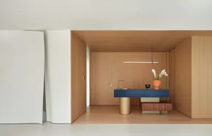 Open modern living area with a kitchen island, dining table, and wooden floors and walls, featuring two potted plants and a warm atmosphere