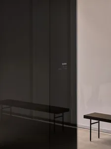 Modern interior space with two tables and a bench in front of a glass wall, featuring clean lines and a minimalist design