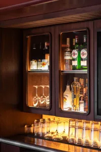 A cozy bar area with liquor bottles and wine glasses, creating a warm and inviting atmosphere for socializing