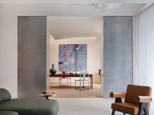Modern living area with a large painting, two chairs, a dining table, and a vase, featuring clean lines and minimalistic elements