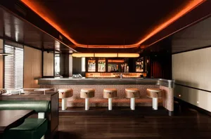 A sophisticated bar area with a long wooden counter, stools, and bottles, creating a comfortable and inviting atmosphere