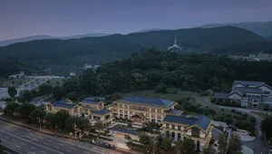 黃牆黑瓦的東方風格住宅建築，樹木環繞，黃昏暖光氛圍