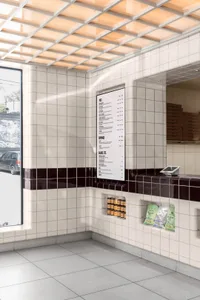Modern restaurant interior with tile walls, large windows, and a menu board on a counter