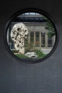 An Asian-style building interior with a large circular window and potted plants adding to the ambiance, creating a unique and inviting atmosphere