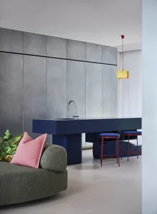 Open living area with a kitchen and dining space, featuring a sink, dining table, chairs, and two couches, with a hanging lamp above the sink