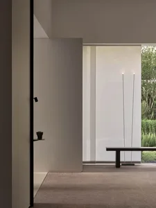 A calm and inviting interior space with a white wall, a bench, candles, and potted plants, featuring a clean and modern aesthetic