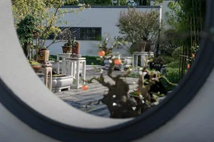 a well-maintained garden with potted plants, trees, benches, and decorative vases