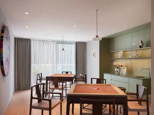 Open dining and kitchen space with wooden tables, natural light, and a clock on the wall