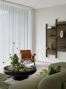 Cozy living area with a large couch, bookshelf, chairs, dining table, potted plants, vases, bowls, and books