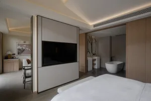 Modern bathroom with a white bathtub, flat screen TV, and neutral-toned walls, creating a clean and airy atmosphere