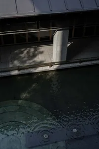 A building with a gold pillar in front of a water feature, surrounded by a glass facade that lets in natural light, creating a bright and inviting atmosphere