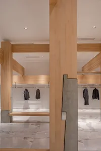 Empty room with wooden walls and floors, featuring hanging clothes and a clean, organized appearance