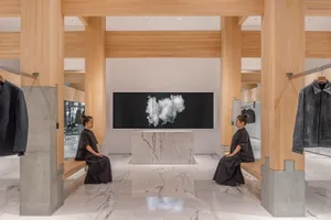 兩位女性坐在長椅上，位於展示牆前，牆上懸掛大型藝術品，背景是大理石地板與精緻裝飾