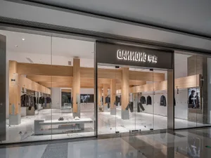 現代店面配備大型玻璃窗，展示身穿黑衣的人體模型，背景乾淨簡約