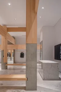 Open modern space with a concrete floor, marble countertop, and hanging clothes on display, creating a clean and minimalistic atmosphere