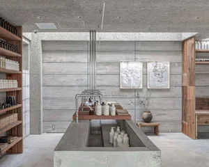 Bathroom with a concrete wall, sink area, and toiletries on the countertop, conveying a clean and organized atmosphere