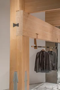 A store display featuring hanging clothes on a wooden rack, creating a sense of organization and cleanliness in a retail environment