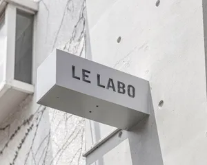 A real photo of a building exterior with white walls, a sign on the side, and natural lighting
