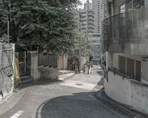 寧靜的都市街景，對面有高樓與樹木，遠處有兩人行走
