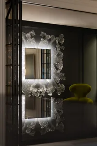 A modern living area with a green chair and ornate mirror, set against a black wall