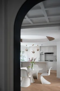 Open kitchen space with white walls and cabinets, two dining tables, and decorative elements adding elegance and warmth