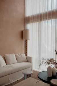 Bright and inviting living room with white furniture, potted plants, and a vase, set against a neutral background