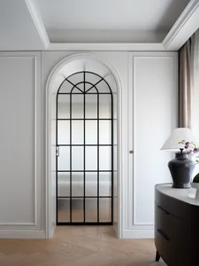 A modern interior space with a wooden door, glass window, mirror, vases, and a potted plant
